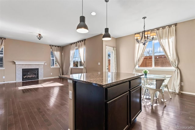 kitchen with dark hardwood / wood-style flooring, decorative light fixtures, dark stone counters, and a kitchen island