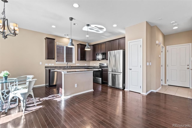 kitchen featuring stainless steel appliances, a kitchen island, sink, and pendant lighting