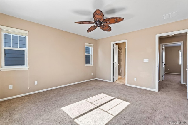 unfurnished bedroom with light carpet, multiple windows, ceiling fan, and ensuite bathroom