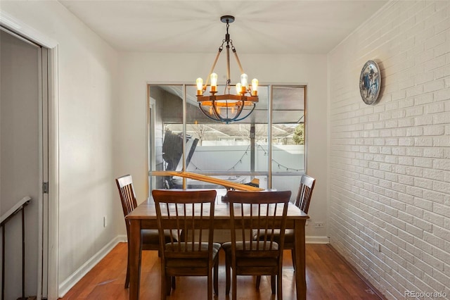 dining space featuring a notable chandelier, dark hardwood / wood-style floors, and brick wall