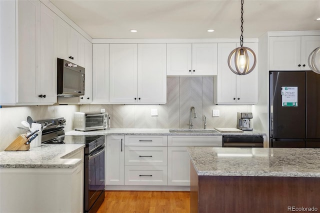 kitchen with decorative light fixtures, tasteful backsplash, sink, white cabinets, and black appliances