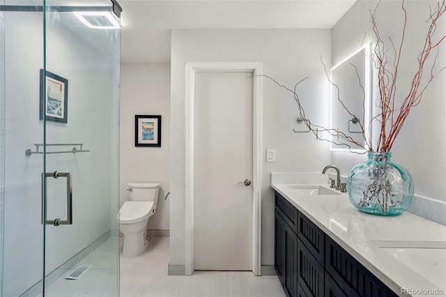 bathroom featuring vanity, toilet, and a shower with shower door