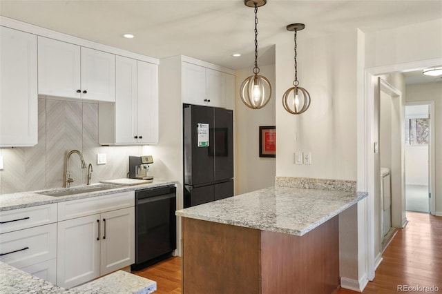 kitchen with a peninsula, a sink, black appliances, light wood-style floors, and white cabinetry