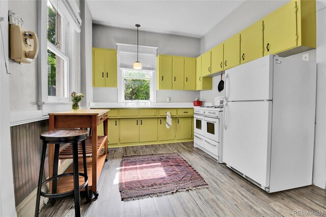 7011 Grandview Ave, Arvada, CO 80002 - kitchen with white appliances, light wood finished floors, light countertops, and yellow cabinets