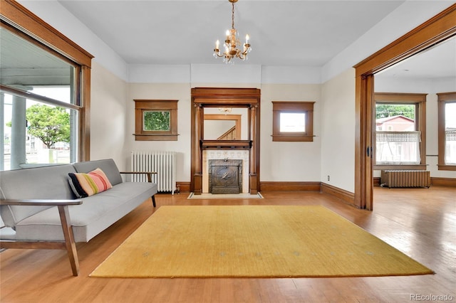 7011 Grandview Ave, Arvada, CO 80002 - living room featuring radiator, a fireplace with flush hearth, wood finished floors, and a chandelier