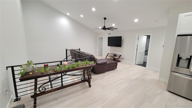 living room with light hardwood / wood-style flooring, lofted ceiling, and ceiling fan