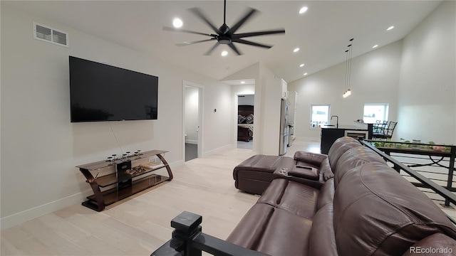 living room with light hardwood / wood-style floors, ceiling fan, and high vaulted ceiling