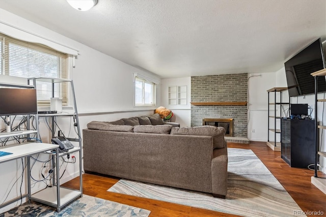 16533 E Baker Pl, Aurora, CO 80013 - living room featuring a brick fireplace, wood finished floors, and a textured ceiling