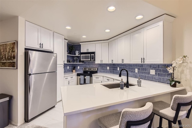 kitchen featuring white cabinetry, sink, stainless steel appliances, and kitchen peninsula