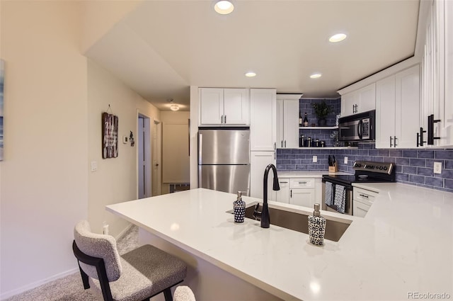 kitchen with a breakfast bar, white cabinetry, backsplash, kitchen peninsula, and stainless steel appliances