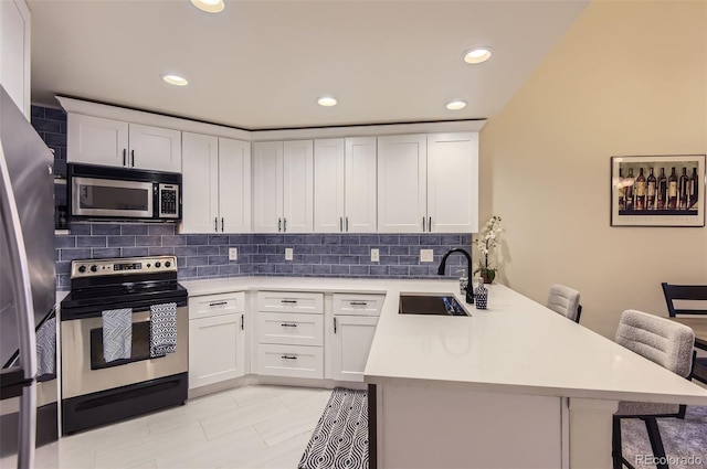 kitchen featuring sink, a kitchen breakfast bar, kitchen peninsula, and appliances with stainless steel finishes