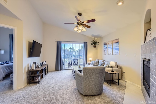 carpeted living room with ceiling fan, vaulted ceiling, and a tile fireplace