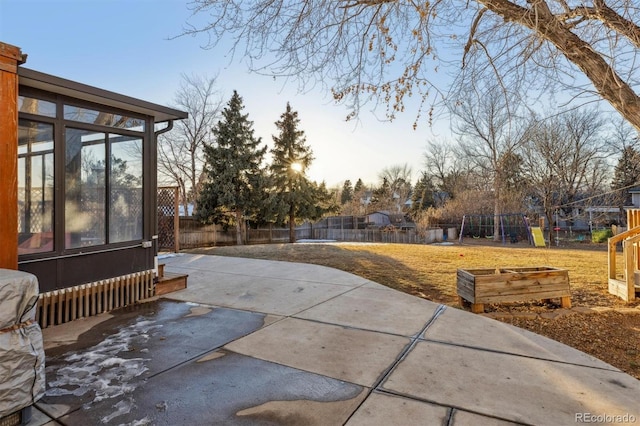 patio terrace at dusk featuring a playground and a sunroom