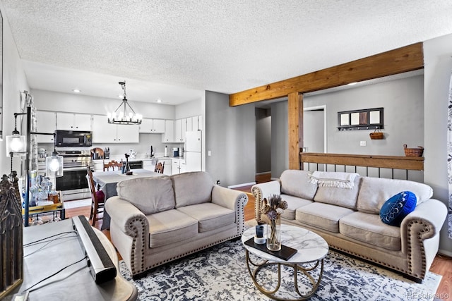 living area featuring an inviting chandelier, baseboards, light wood finished floors, and a textured ceiling