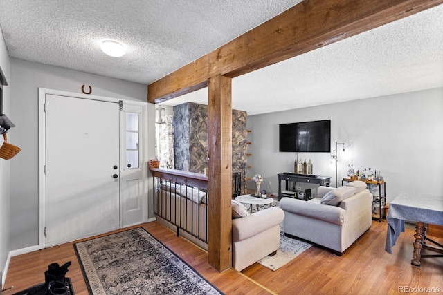 foyer featuring beamed ceiling, a textured ceiling, and wood finished floors