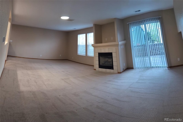 unfurnished living room with a fireplace, light carpet, baseboards, and visible vents