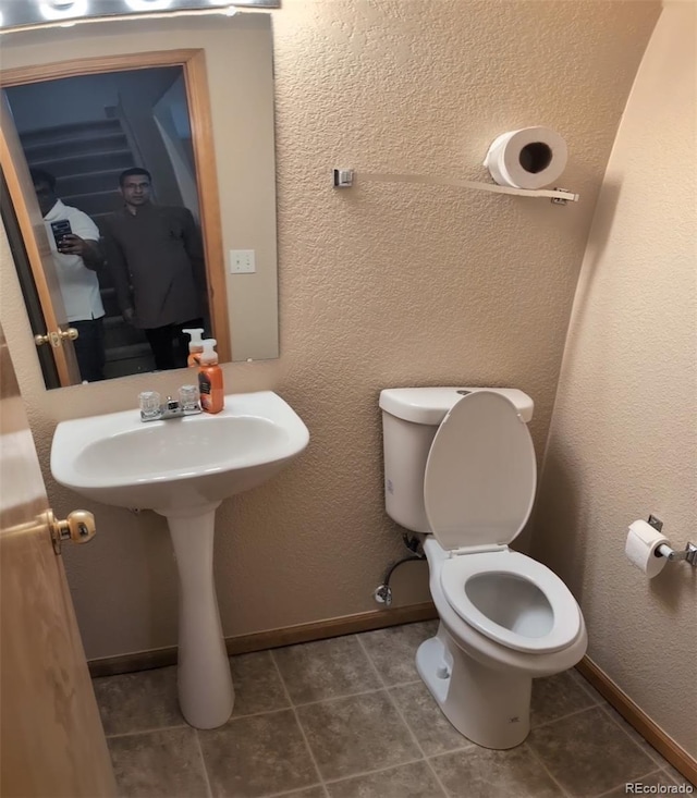 half bathroom with toilet, tile patterned flooring, and baseboards