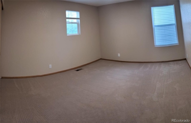 empty room featuring light carpet, baseboards, and visible vents