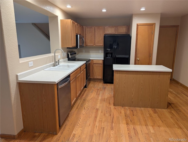 kitchen with light wood finished floors, a center island, a sink, light countertops, and appliances with stainless steel finishes