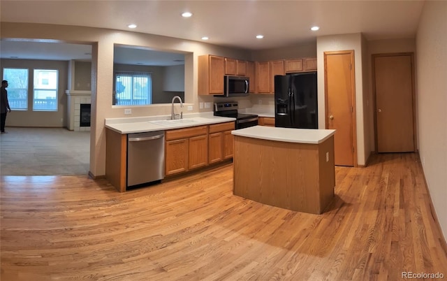 kitchen with a sink, stainless steel appliances, recessed lighting, light countertops, and light wood-style floors