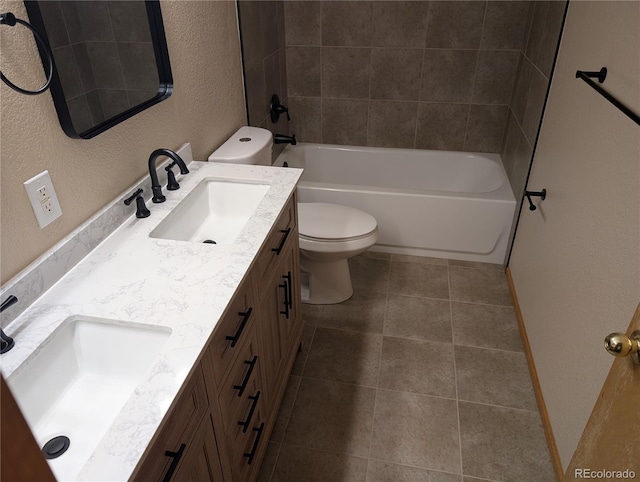 bathroom featuring double vanity, a textured wall, toilet, and a sink