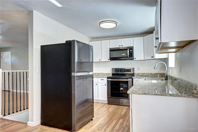 7704 Newland St, Arvada, CO 80003 - kitchen featuring stainless steel appliances, light wood-type flooring, light stone counters, and white cabinets