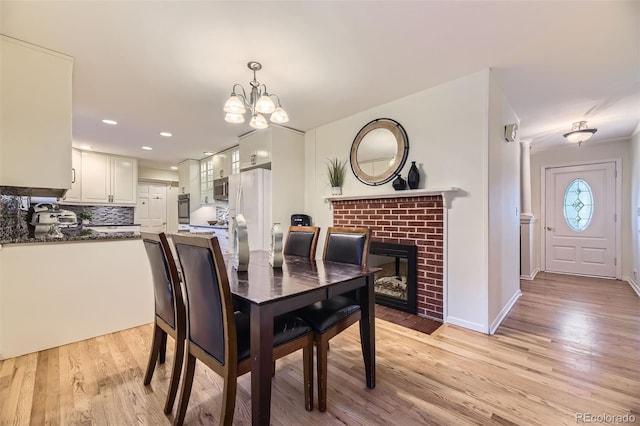 5857 S Logan Ct, Centennial, CO 80121 - dining room with light wood finished floors, a chandelier, a fireplace, and recessed lighting