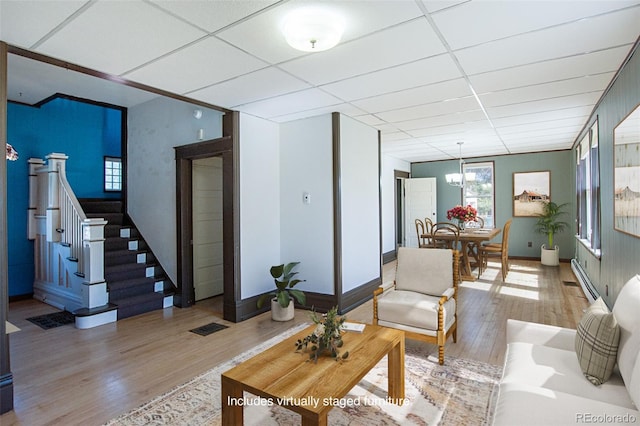 living room with a paneled ceiling and light wood-type flooring