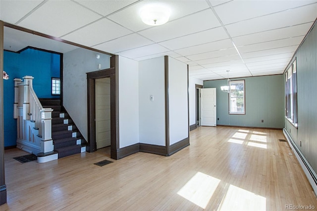 unfurnished room featuring a paneled ceiling, a notable chandelier, light hardwood / wood-style floors, and a baseboard radiator