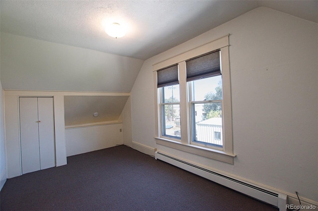 bonus room featuring baseboard heating, a textured ceiling, vaulted ceiling, and dark colored carpet