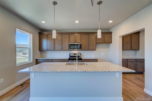 16858 Greyhawk Dr, Monument, CO 80132 - kitchen featuring decorative backsplash, a kitchen island with sink, light wood-type flooring, a sink, and stainless steel appliances