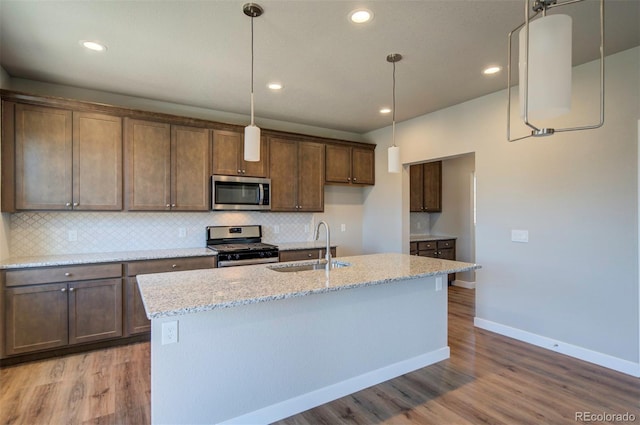 16858 Greyhawk Dr, Monument, CO 80132 - kitchen with baseboards, a sink, light wood-style flooring, appliances with stainless steel finishes, and backsplash