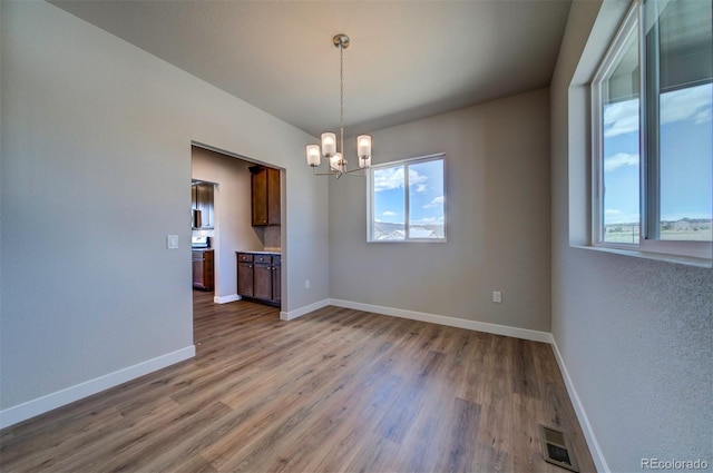 16858 Greyhawk Dr, Monument, CO 80132 - unfurnished dining area featuring visible vents, baseboards, wood finished floors, and an inviting chandelier