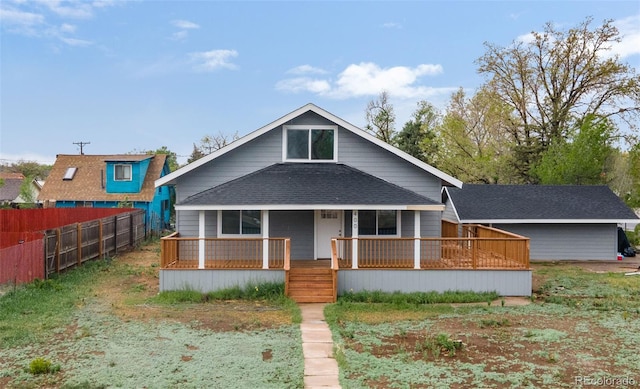 view of front facade with covered porch, fence, and roof with shingles