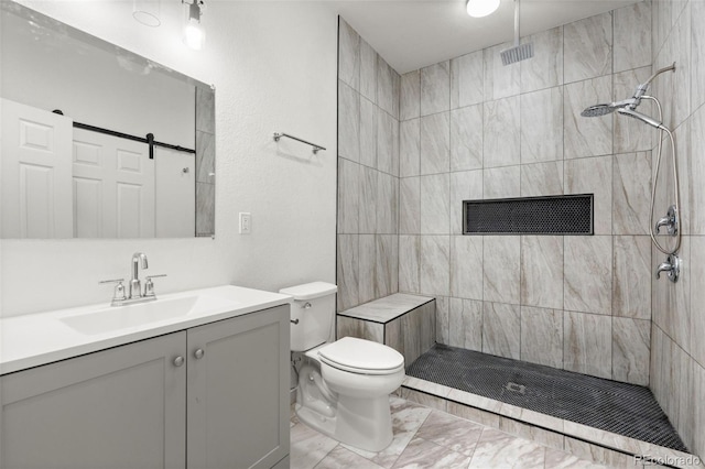 bathroom with marble look tile flooring, a tile shower, vanity, and toilet