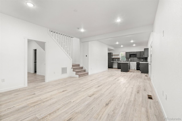 unfurnished living room with light wood-style floors, stairs, recessed lighting, and baseboards
