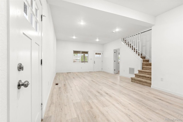 unfurnished living room with stairway, recessed lighting, light wood-style flooring, and baseboards