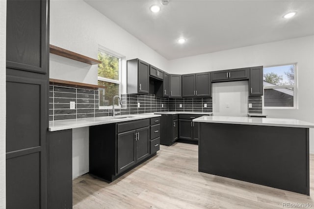 kitchen with a sink, decorative backsplash, light wood finished floors, and recessed lighting