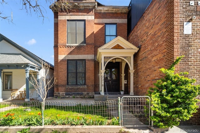 2318 Arapahoe St, Denver, CO 80205 - view of front facade featuring brick siding, a fenced front yard, and a gate