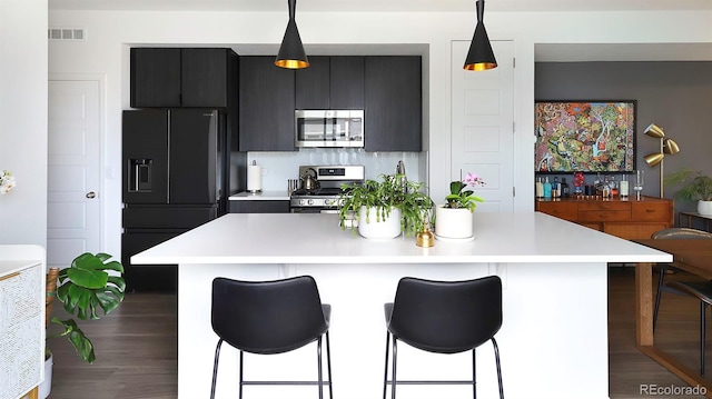 kitchen featuring a kitchen island, visible vents, light countertops, appliances with stainless steel finishes, and a kitchen bar