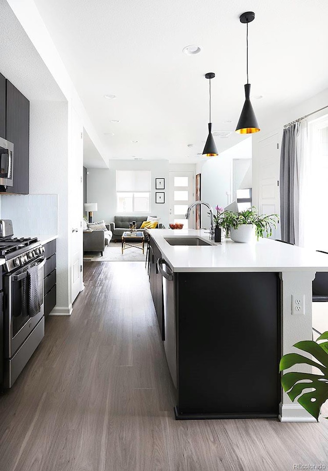 kitchen with a sink, stainless steel appliances, light countertops, and dark wood-style floors