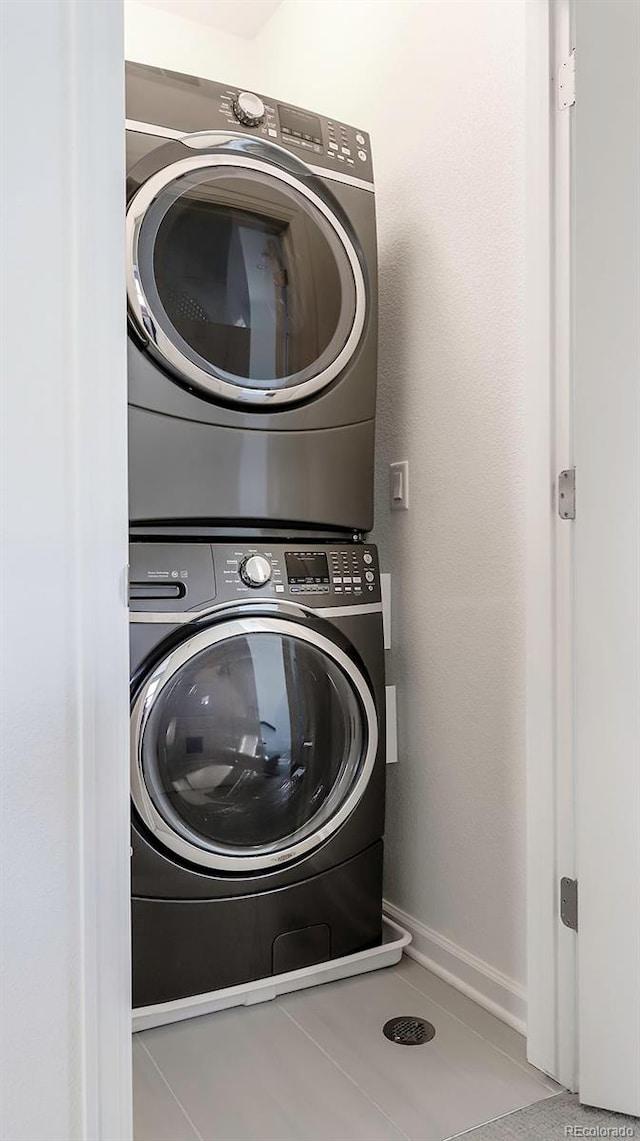 laundry area with baseboards, laundry area, and stacked washer / drying machine