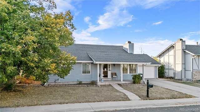 view of front of property with roof with shingles, a chimney, covered porch, a garage, and driveway