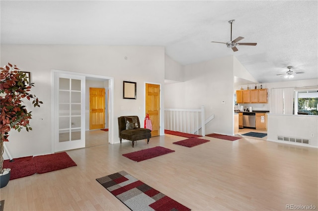 interior space with lofted ceiling, light wood finished floors, a textured ceiling, and visible vents