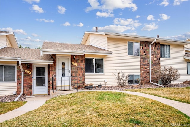 tri-level home with a shingled roof and a front lawn