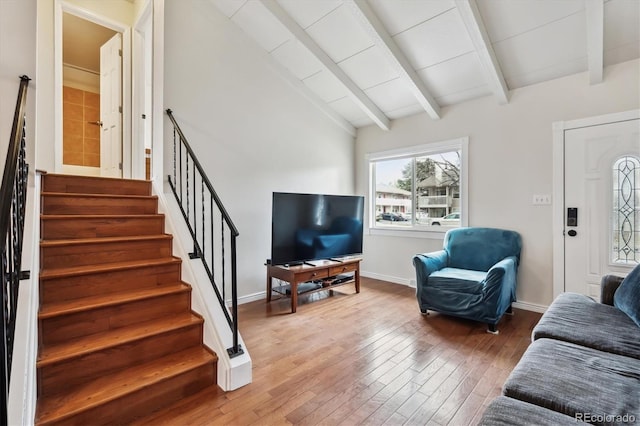 living room featuring baseboards, lofted ceiling with beams, wood finished floors, and stairway