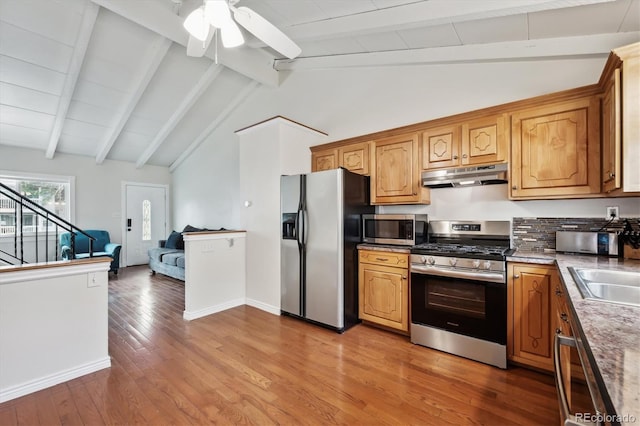 kitchen featuring vaulted ceiling with beams, a ceiling fan, under cabinet range hood, and stainless steel appliances