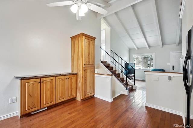 staircase featuring lofted ceiling with beams, hardwood / wood-style flooring, ceiling fan, and visible vents