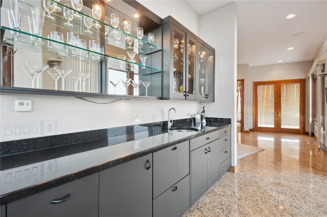 bar with sink, dark stone counters, and french doors