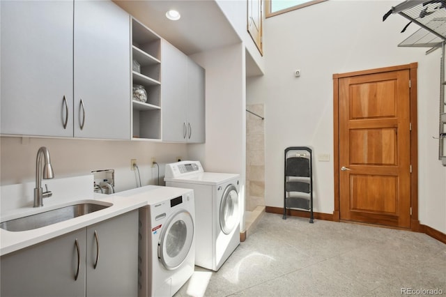 washroom with cabinets, washing machine and dryer, and sink